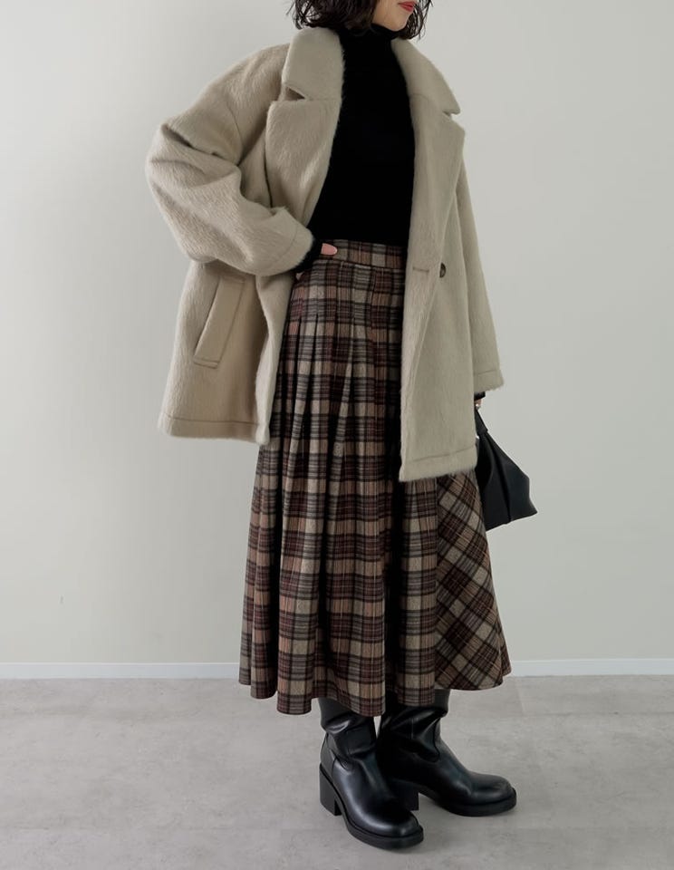 Woman in black turtleneck sweater with plaid wool coat and heeled boots